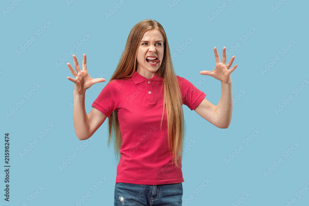 Fototapeta premium Portrait of an angry woman looking at camera isolated on a blue background