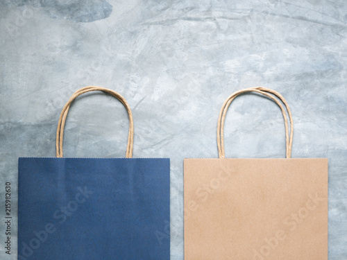 Top view blue and brown paper shopping bag on wall concrete texture background, Mock-up of blank blue and brown paper shopping bag and copy space. Flat lay.