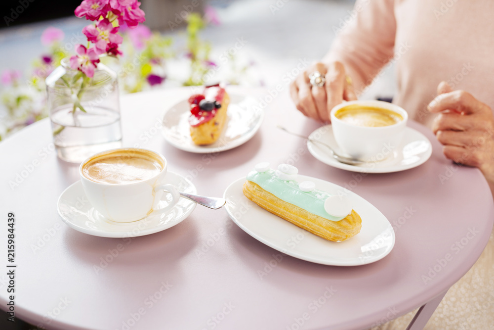 Happy hours. Close up of yummy eclair and coffee waiting on table Happy hours. Close up of yummy eclair and coffee waiting on table