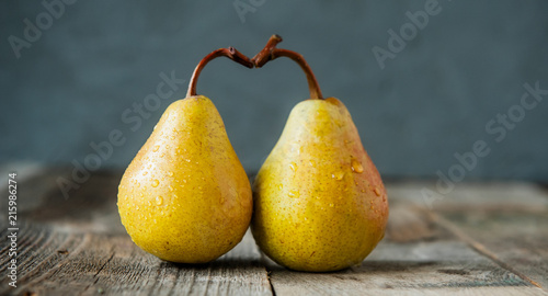 A couple of Fresh ripe organic yellow pears form the shape of the heart on rustic wooden table on the dark gray stone background. Relations, love. care concept. Selective focus, wide. Space for text.