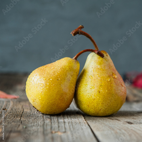 Autumn harvest concept -a couple of Fresh ripe organic yellow pears with water drops on rustic wooden table, dark stone background. Vegetarian, vegan, healthy diet food. Selective focus