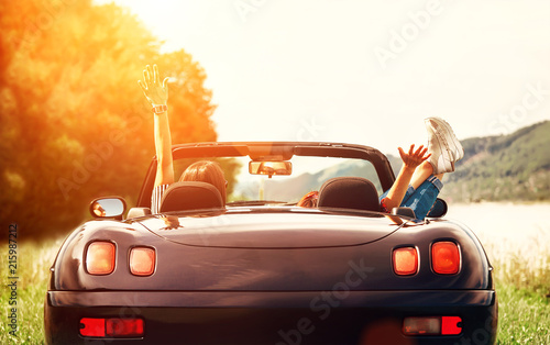 Two girls travelers sit in cabriolet car and enjoy with beautiful view photo