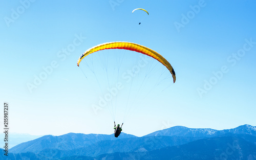 Two Paragliders soaring in the sky over the blue mountains