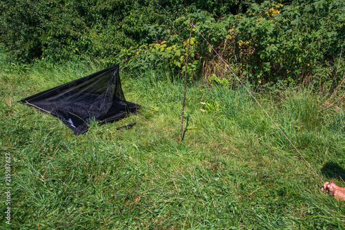 Ein Personen Zelt wird befestigt mit Stock und Seil, Hand im Bild