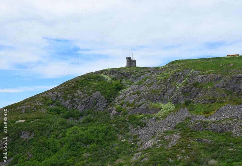 looking up from the hiking path on the bottom of Signal Hill covered with lush green grass towards the tower, St John's Newfoundland Canada