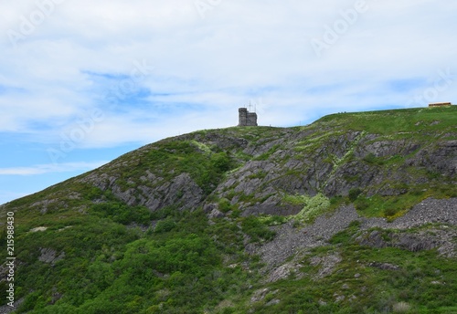 looking up from the hiking path on the bottom of Signal Hill covered with lush green grass towards the tower, St John's Newfoundland Canada