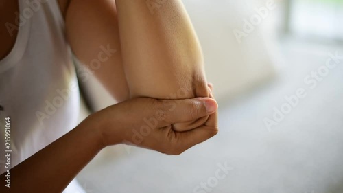 Wallpaper Mural Closeup young woman sitting on sofa and feeling elbow pain and she massage her elbow at home. Healthcare and medical concept. Torontodigital.ca