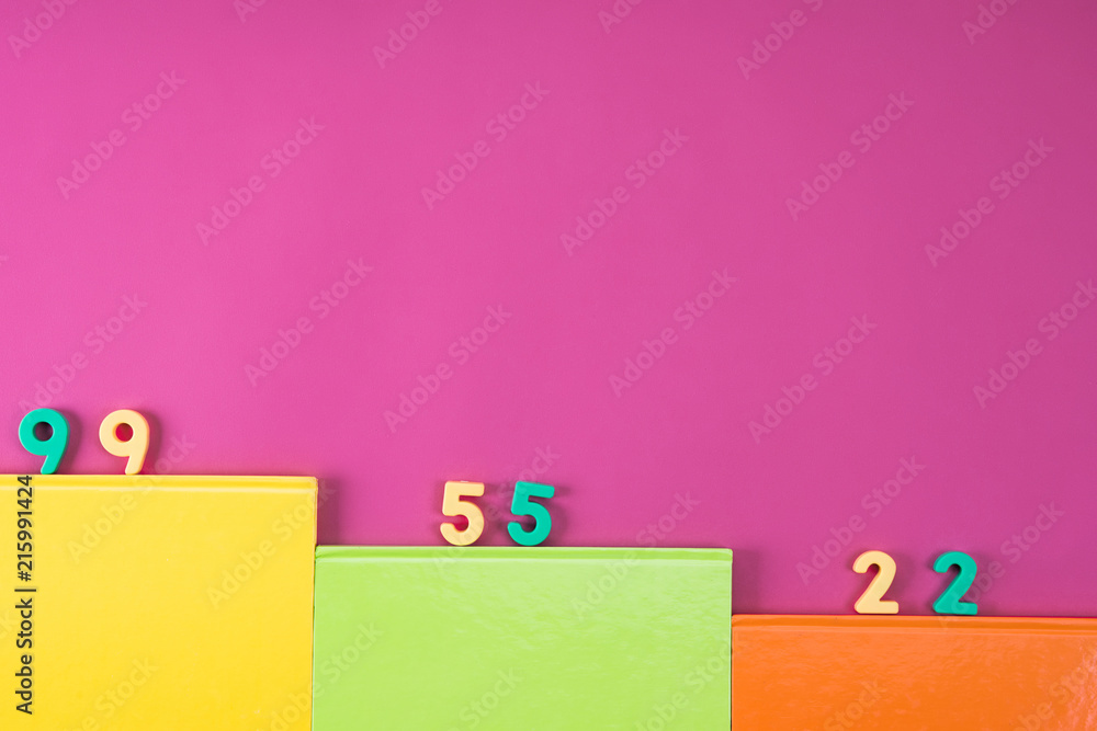top view of colorful notebooks and math education numbers on pink top view of colorful notebooks and math education numbers on pink