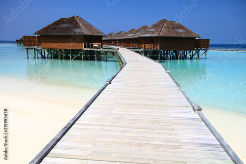 Wood Pier Leading to Overwater Bungalows on Pacific Ocean in the Maldives