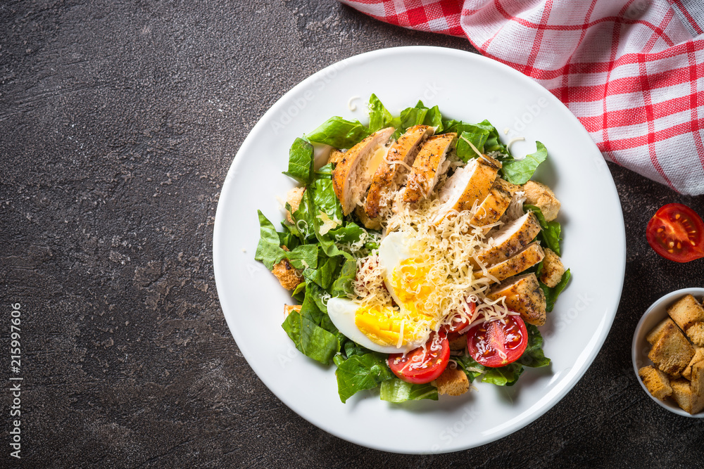 Caesar salad with chicken breast and tomatoes.