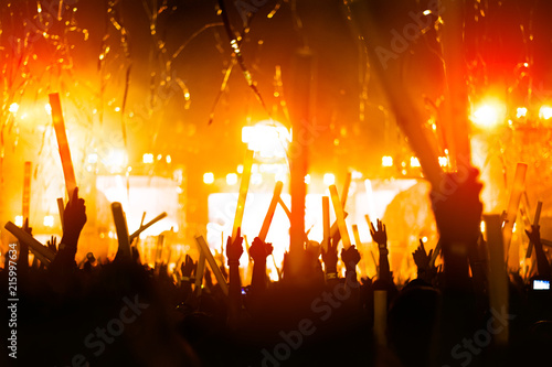 silhouettes of hand in concert.Light from the stage.confetti.the crowd of people silhouettes with their hands up