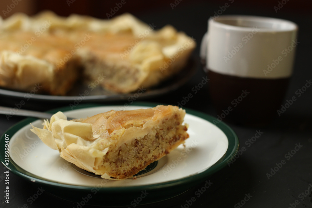 Apple cake with almond cream on a dark background. Baked cake with coffee and teaspoon.  Pie for the whole family on a sunny day