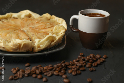 Apple cake with almond cream on a dark background. Baked cake with coffee nd coffee beans. Pie for the whole family on a sunny day