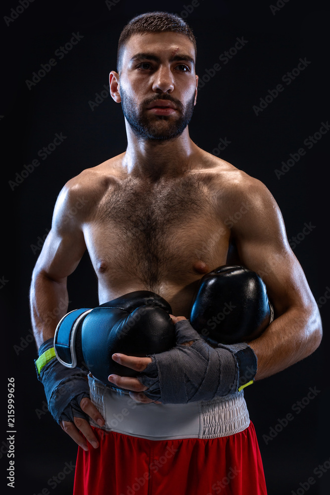 Man's hands in boxing bandages holds boxing gloves on a black background.