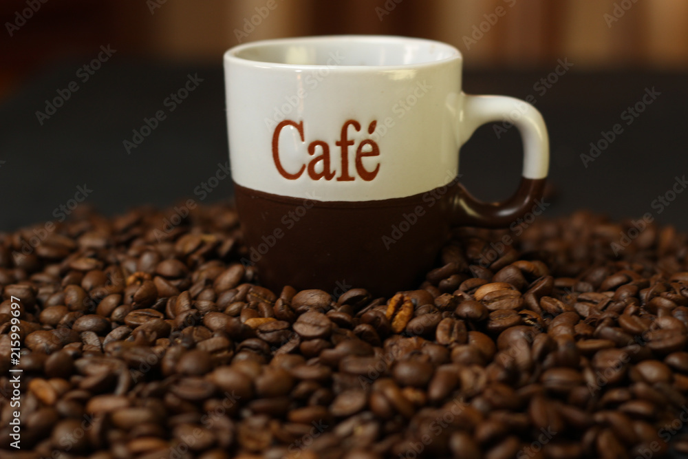 Fototapeta premium A cup of coffee with coffee beans on a dark background. A delicious fragrant coffee of the best varieties
