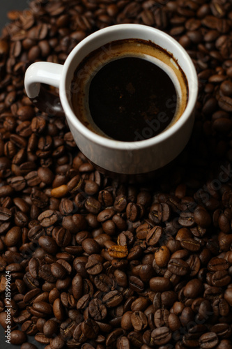 A cup of coffee with coffee beans on a dark background. A delicious fragrant coffee of the best varieties