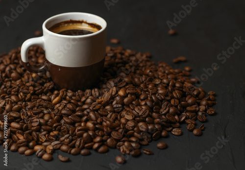 A cup of coffee with coffee beans on a dark background. A delicious fragrant coffee of the best varieties