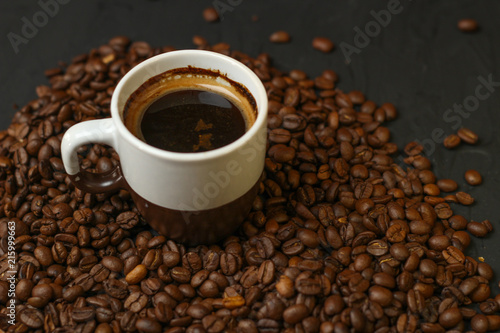 A cup of coffee with coffee beans on a dark background. A delicious fragrant coffee of the best varieties © Yaroslav
