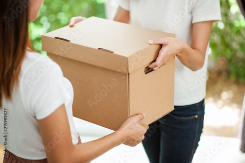 Close up of two women's hands helping each other moving boxes into their new home. © Day Of Victory Stu.