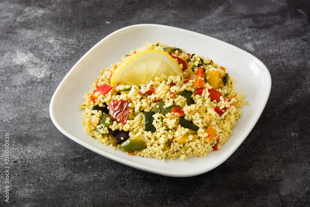 Couscous with vegetables on black stone. 