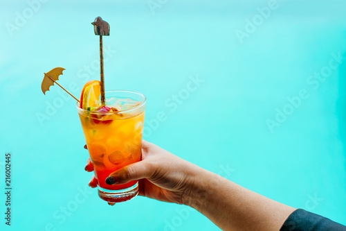 Woman holds a cocktail on swimming pool background.fresh tropical juice cocktail served pool side in Belize.