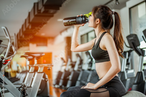 young fitness woman tired in gym drink protein shake.exercising concept.fitness and healthy lifestyle