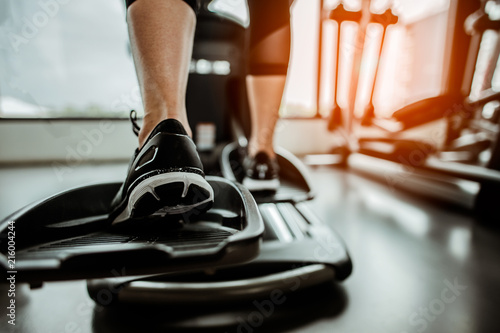 Closeup leg of cardio workout on an elliptical.people working out on an elliptical trainer in gym.Back view photo