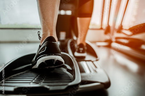Closeup leg of cardio workout on an elliptical.people working out on an elliptical trainer in gym.Back view