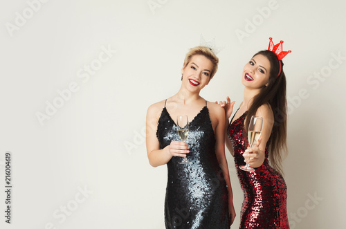 Happy girls with party makeup drinking champagne at white background