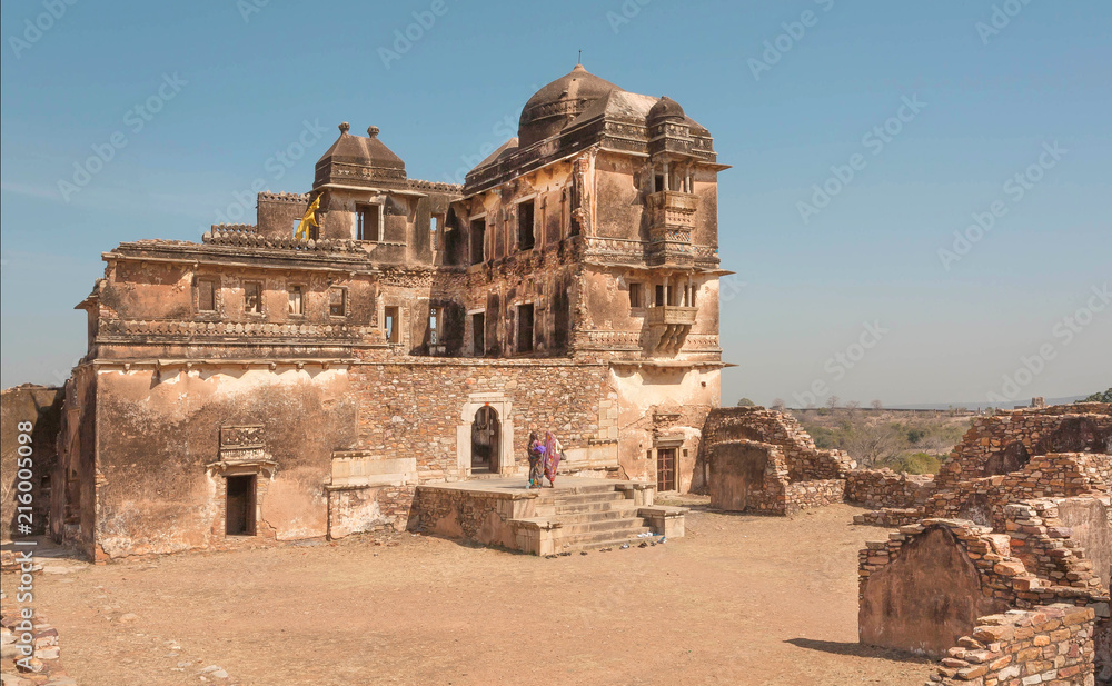 Old destroyed palace with brick towers and some indian women in sari, India.
