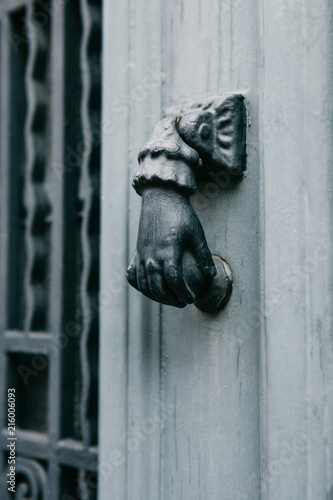 Close-up. Vintage handle for knocking on the door in the form of a hand. Entrance to the apartment building.