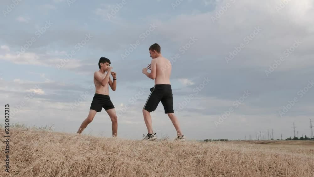 A view of two boys fighting on a training far away from the city A view of two boys fighting on a training far away from the city