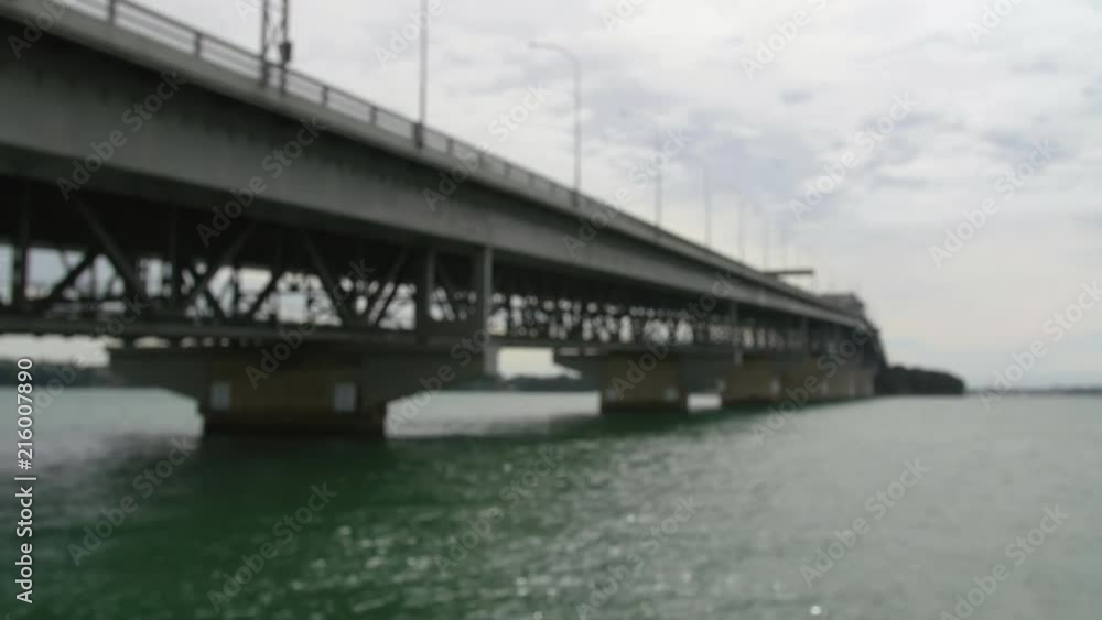 Large harbour bridge low angle defocussed perspective with busy commuter traffic passing over. Auckland New Zealand. Large harbour bridge low angle defocussed perspective with busy commuter traffic passing over. Auckland New Zealand.