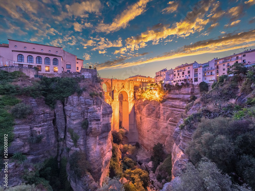 Puente Nuevo bridge and the houses built on the edge of the cliff at dusk, in the ancient city of Ronda, Spain. photo