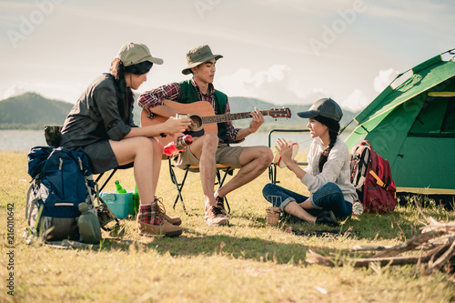 group of young people enjoy in music of drums and guitar on camping trip.