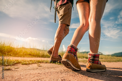 Hikers with backpacks walking trough forest path wearing mountain boots with focus on the shoes.