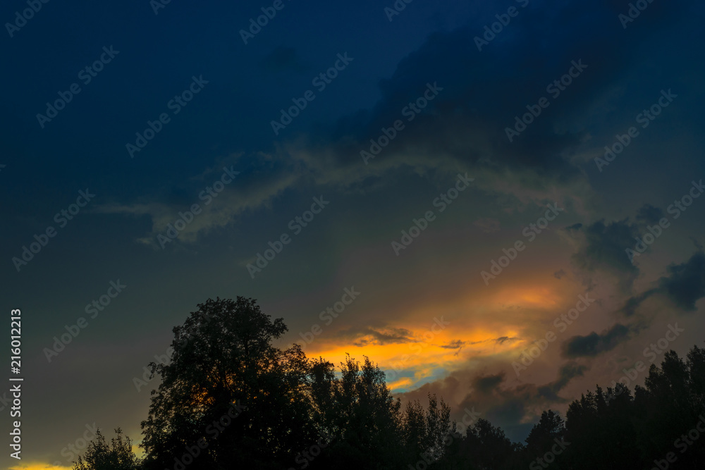 Beautiful view of sunset storm cloud formation enlightened with last yellow sunbeams and visible blue sky