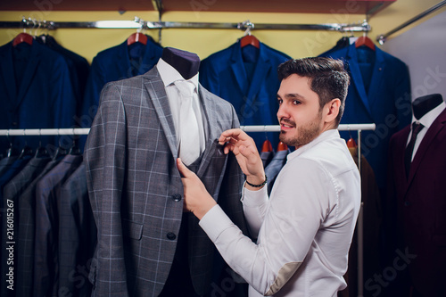 Tailor, tailoring. Men's suit, tailor in his workshop. Elegant man's suits hanging in row. Luxury mens classic suits on rack in elegant men's boutique. photo