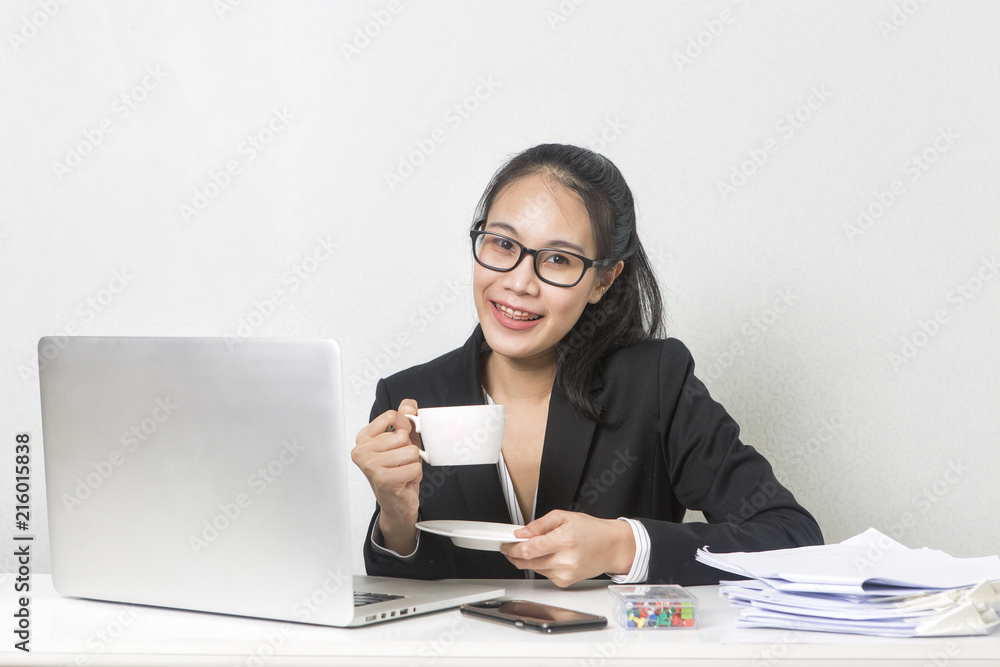 Happy business Asian woman working with laptop at white working table, diligent professional working woman drinking coffee while working on laptop computer. Happy business Asian woman working with laptop at white working table, diligent professional working woman drinking coffee while working on laptop computer.