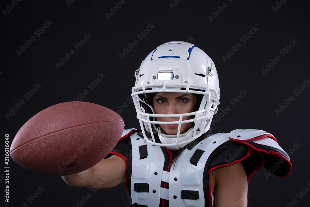 Naklejka premium Portrait of sexy attractive young girl in a sports outfit for rugby with the helmet strongly looking forward standing on black background