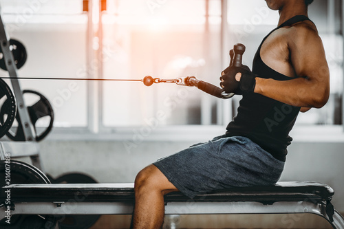 Fototapeta young man making low cable pulley row seated