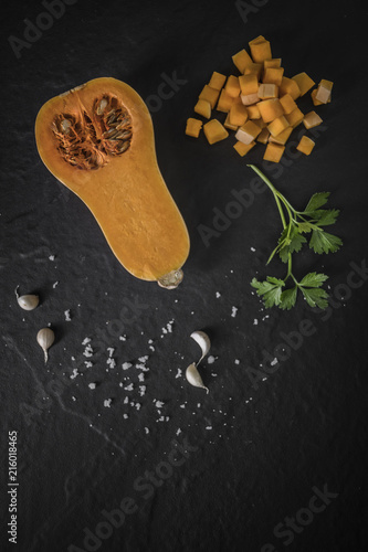 organic butternut squash with spices and ingredients for making on a black slate,