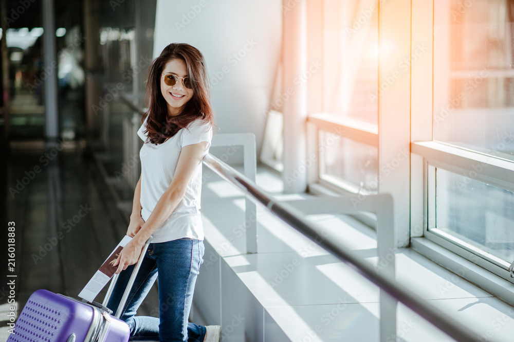 Young woman pulling suitcase in modern airport terminal. Travelling guy with his luggage while waiting for transport. Rear view. Copy space Young woman pulling suitcase in modern airport terminal. Travelling guy with his luggage while waiting for transport. Rear view. Copy space