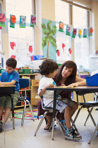 A teacher helping a student in a kindergarten classroom. 