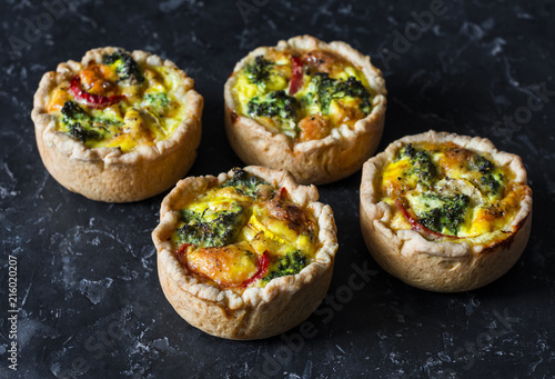 Broccoli cheddar mini savory pies on dark background, top view. Delicious appetizers, snack, tapas