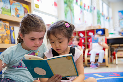 Two classmates reading a book in s kindergarten classroom. 