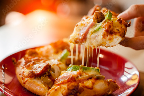 A slice of pizza in hand.Hot pizza slice with melting cheese.