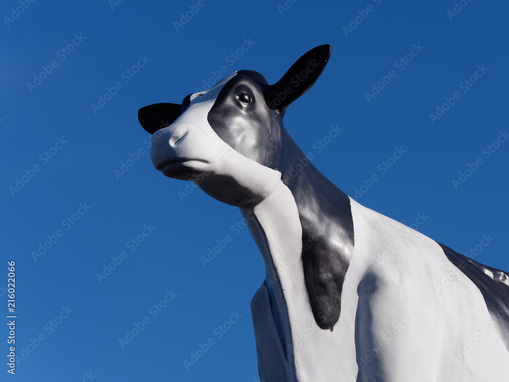 black and white cow statue against a pure blue sky