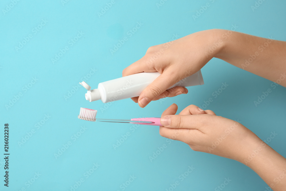 Woman squeezing toothpaste on brush against color background Woman squeezing toothpaste on brush against color background