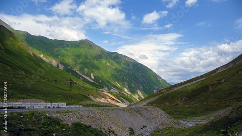 Green mountain landscape with clouds. Road at the foot of the mountain